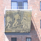 Balkon mit Wandbild: Hafenarbeiter tragen Säcke auf der Schulter