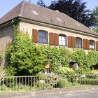 Wohnhaus mit grünen Ranken und braunen Fensterläden