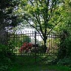 Verschlossenes Tor mit blühendem Garten dahinter