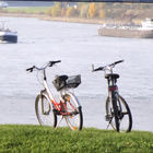 Blick auf zwei am Ufer stehende Fahrräder, die vorbeifahrende Schiffe beobachten