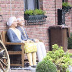 Älteres Paar sitzt auf Bank vor Haus