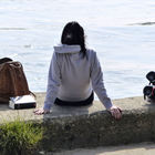 Frau sitzt am Ufer und betrachtet den Rhein