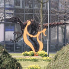 Blühende Narzissen und tanzende Stahlfiguren vor rostigem Dinosaurier